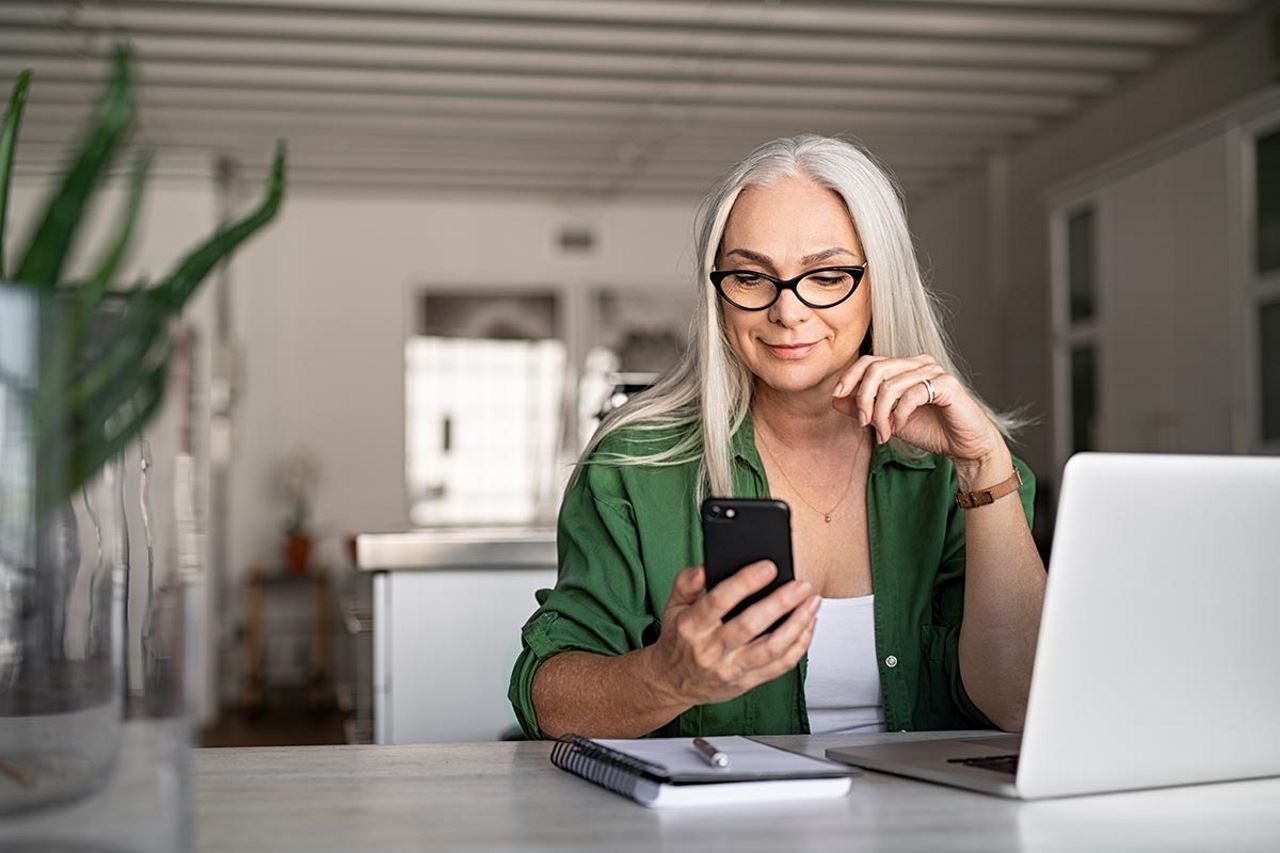 Professional woman working from home and looking at her phone