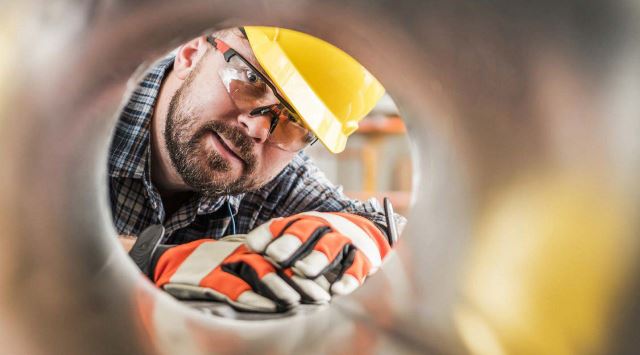 man in hardhat adjusting a pressure gauge