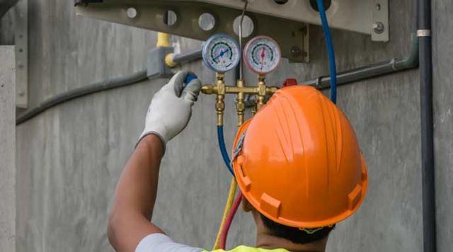 man in hardhat adjusting pressure gauge