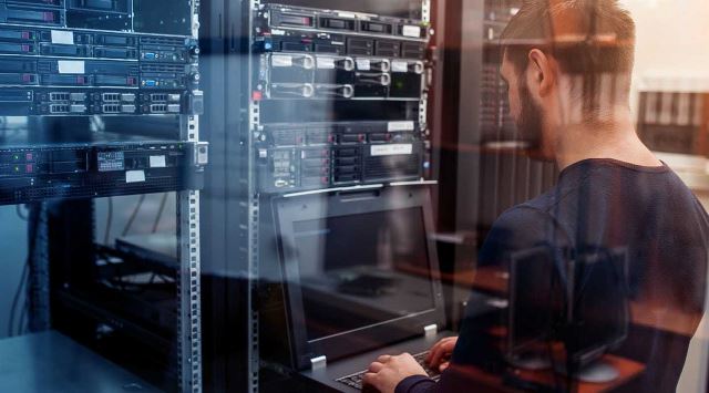 IT worker at a laptop in a server room