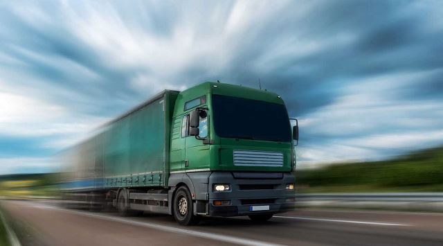 Green semi driving fast down the highway