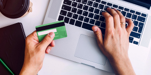 Person with credit card and laptop at desk